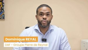 Un homme en chemise bleu clair est assis à un bureau et porte un petit microphone. Le texte à l'écran est le suivant : "Dominique REYAL, DAF - Groupe Pierre de Reynal" : "Dominique REYAL, DAF - Groupe Pierre de Reynal", alors qu'il parle d'outils financiers comme Agicap et Sinergis.